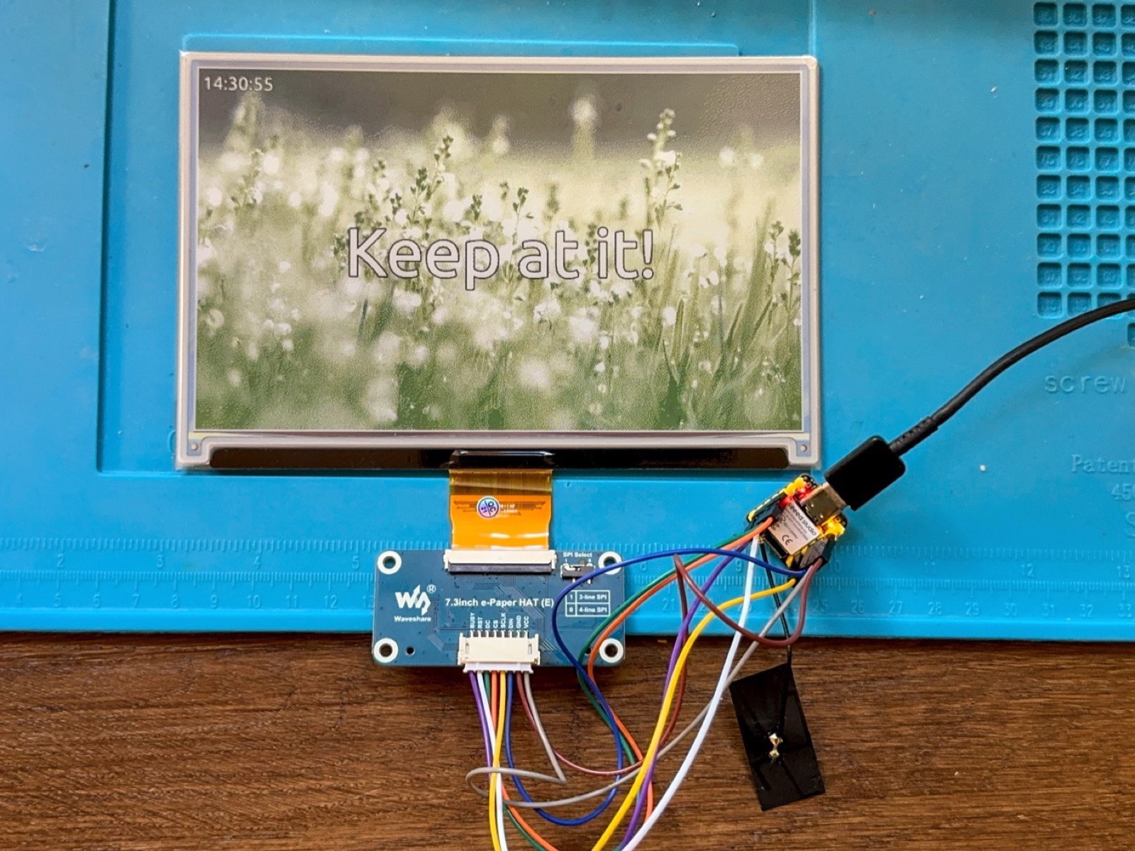 An ESP32-S3 wired to a 7.3 inch Waveshare e-paper panel, showing a rendered scene